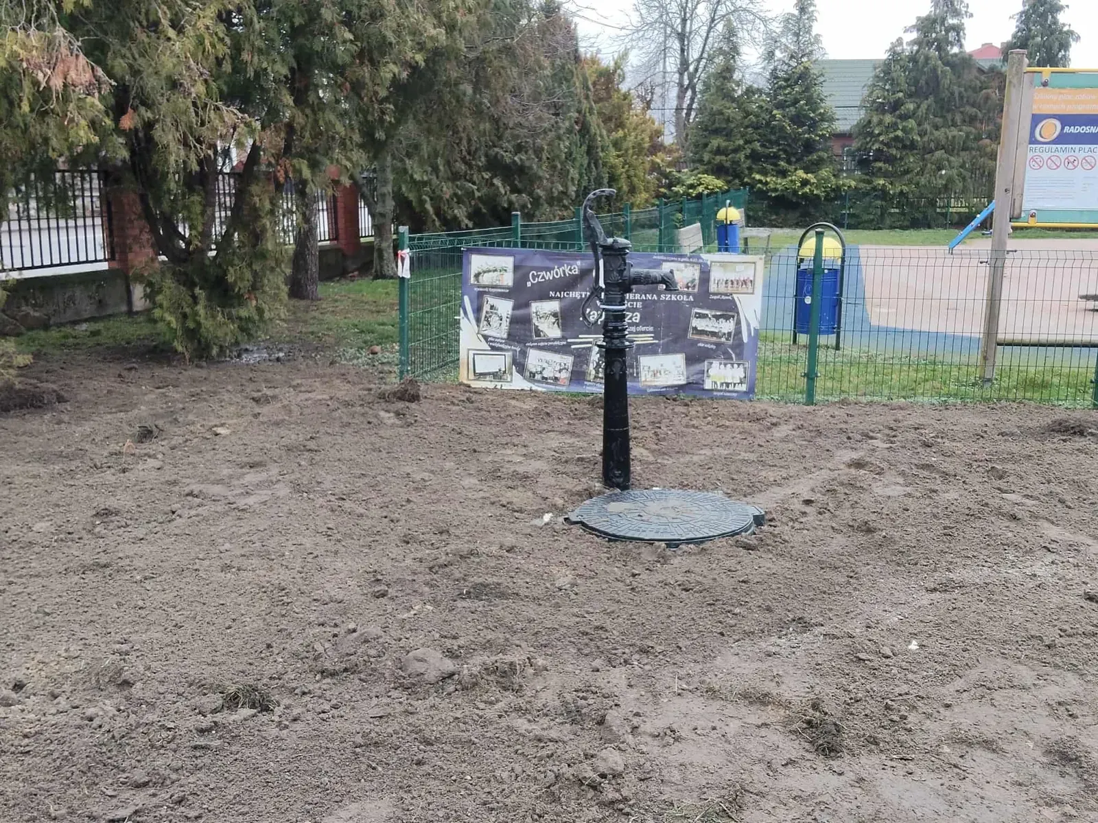 Czarna pompa ręczna na studni na terenie przy placu zabaw